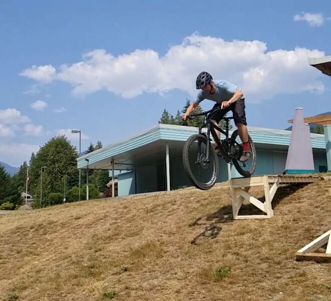 A rider executing a drop maneuver to a sloped landing during a mountain bike skills camp with RideHub