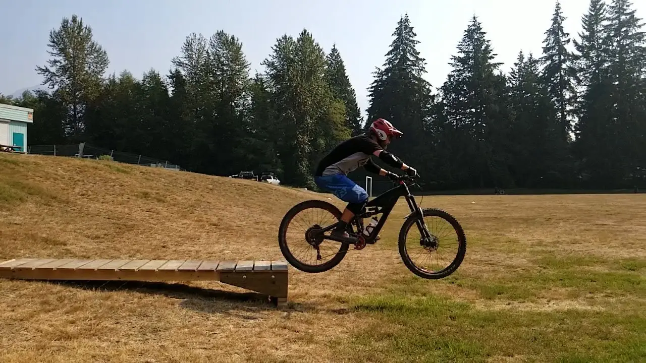 Private Instruction 1 A person embarking on an adventurous mountain bike ride in Squamish, showcasing their skills on a wooden ramp.