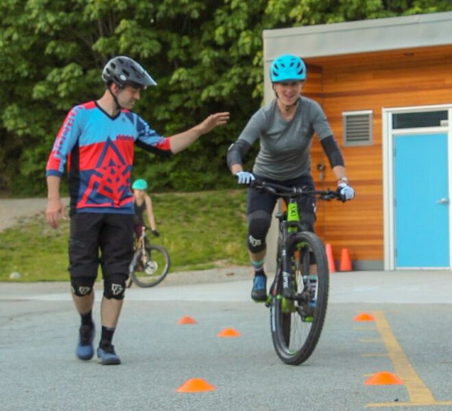 A client having fun while learning a challenging skill on their mountain bike in Squamish