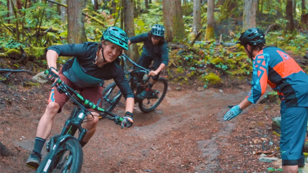 Service Training Course 2 Three mountain bikers enjoying a thrilling ride down a trail in the woods.