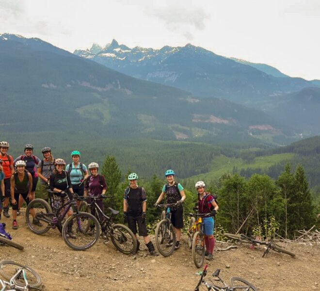 A large group of women at the top of the trails, overlooking Squamish and the mountains