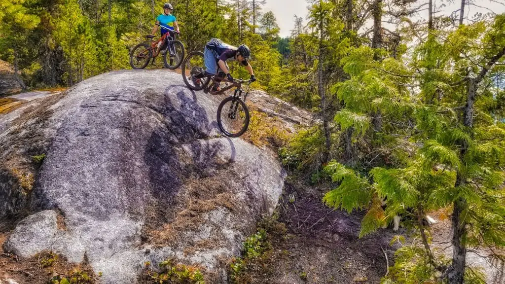 Service Training Course 3 Two mountain bikers on top of a rock enjoying the stunning view while sipping coffee.