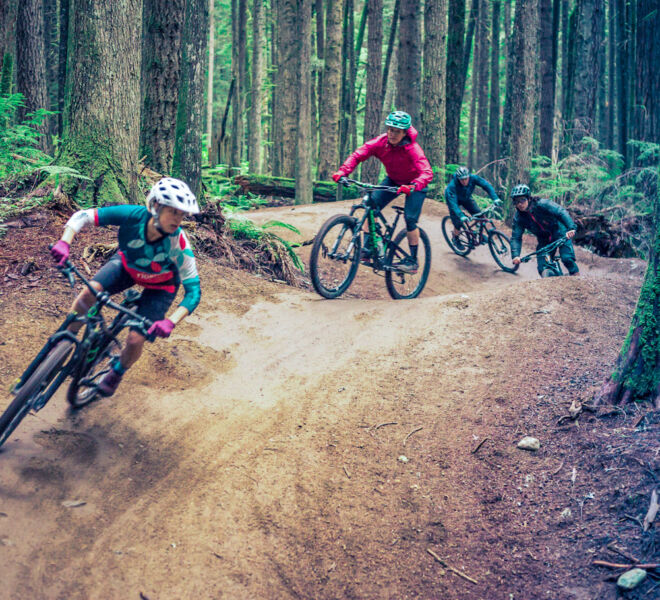 A group of 4 riders in a train riding down the famous corners of the Half Nelson mountain biking trail