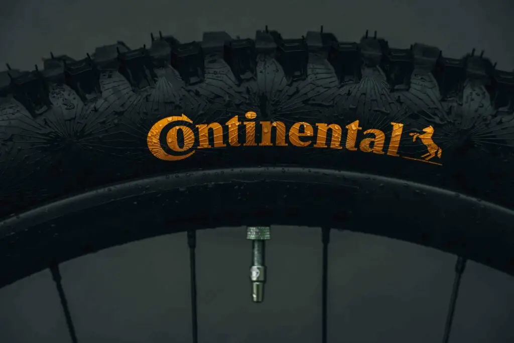 Shop 5 Close-up of a Continental tire on a bicycle wheel, showing the brand’s yellow logo and tread pattern.